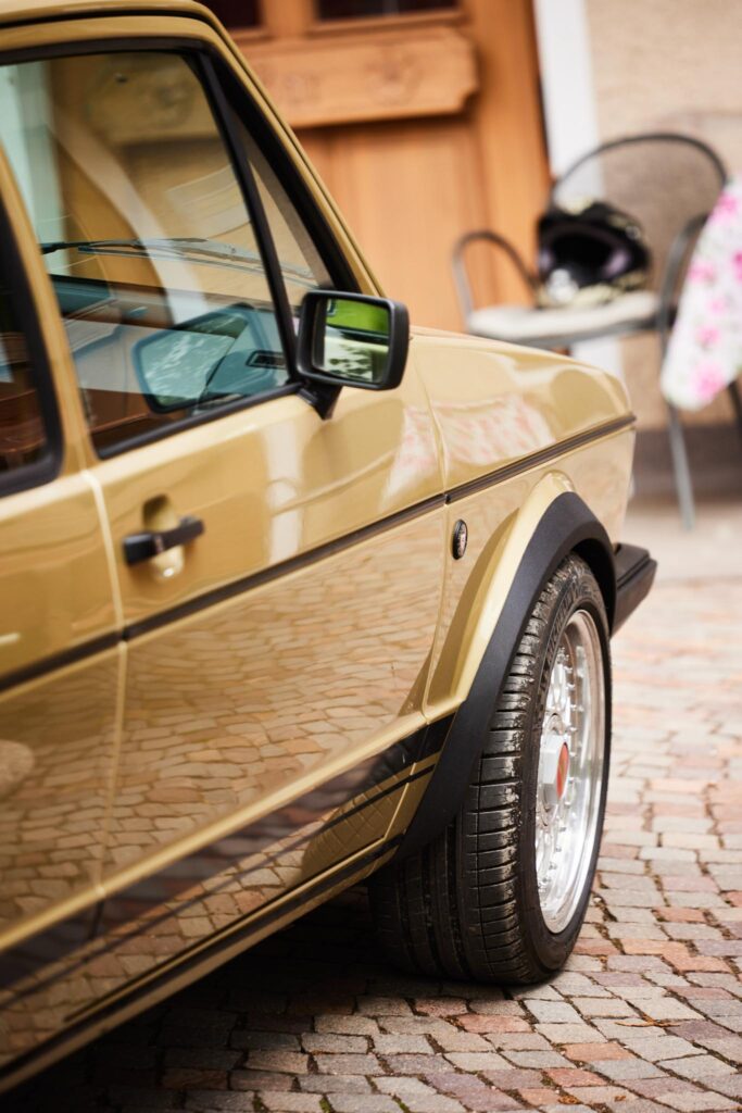 Detailaufnahme eines goldfarbenen Autos auf Kopfsteinpflaster