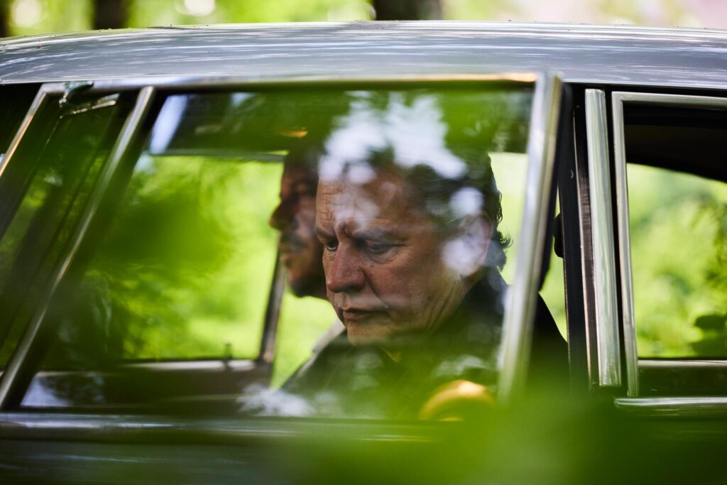 Männer im Auto, nachdenklich, von Pflanzen verdeckt