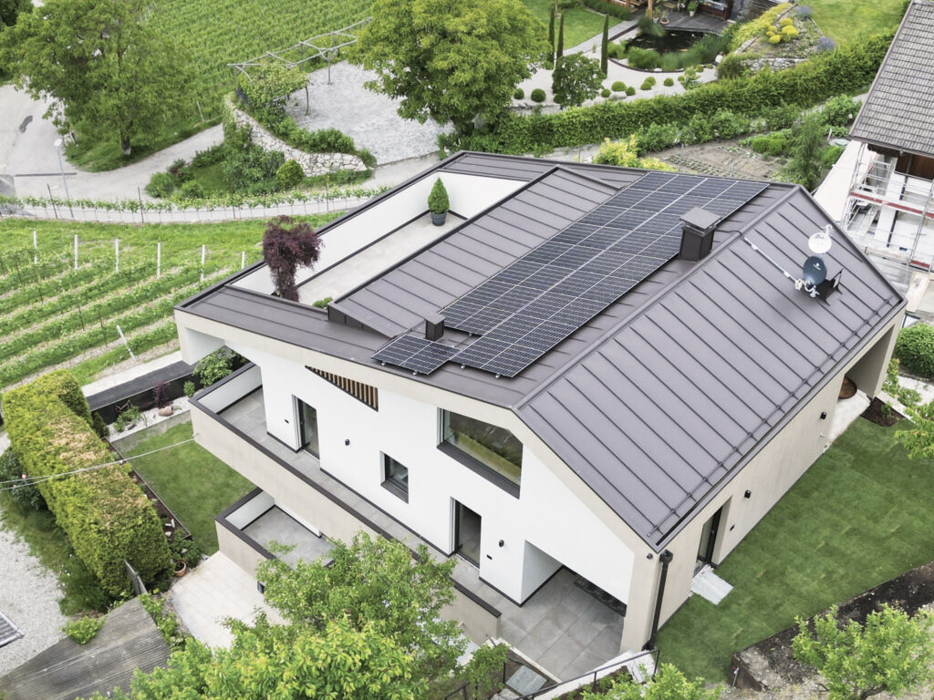 Modernes Haus mit Solarpanelen, eingebettet in grüne Landschaft