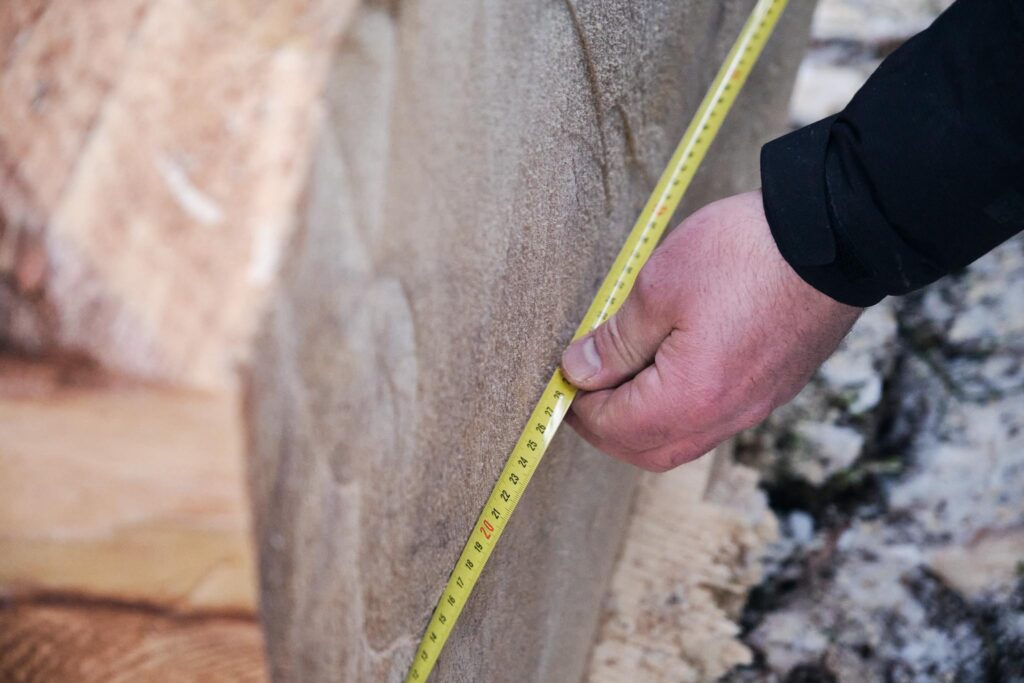 Detailaufnahme einer Messung mit Maßband an Holzplatte
