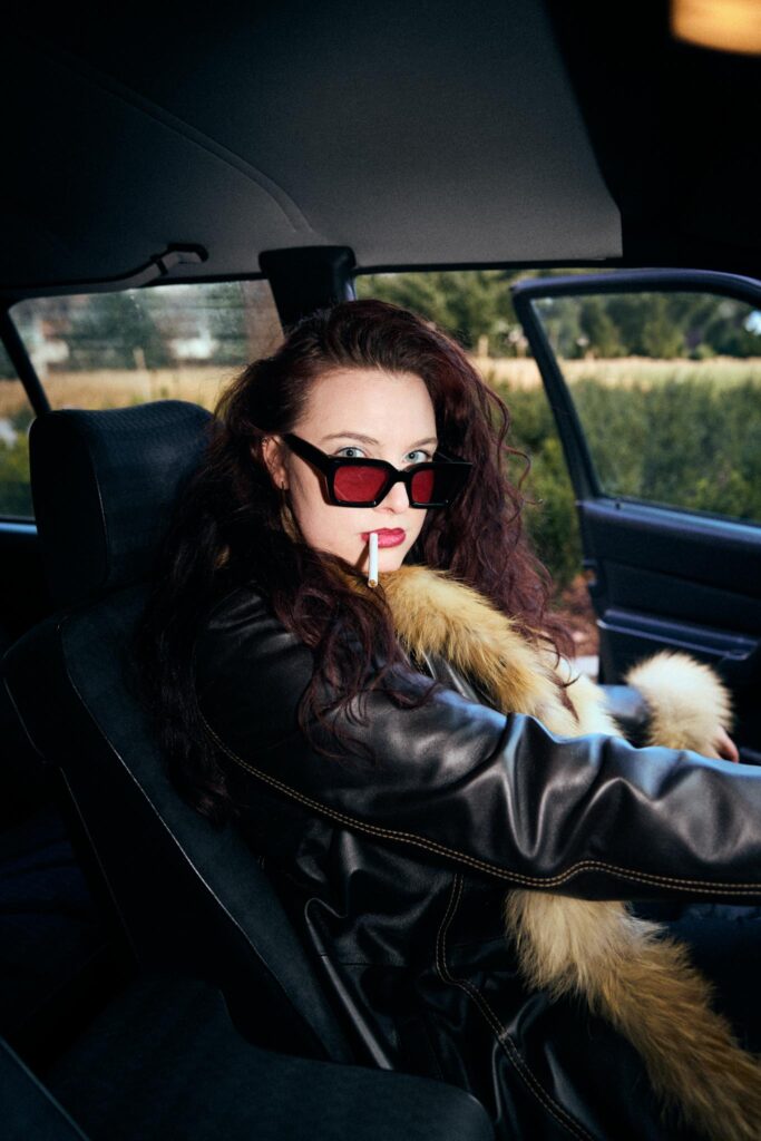 Frau mit Sonnenbrille und Zigarette im Auto sitzend