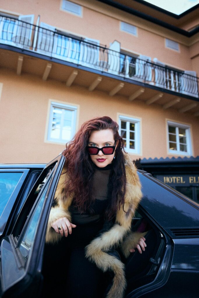 Frau mit Sonnenbrille steigt aus Auto vor Hotel