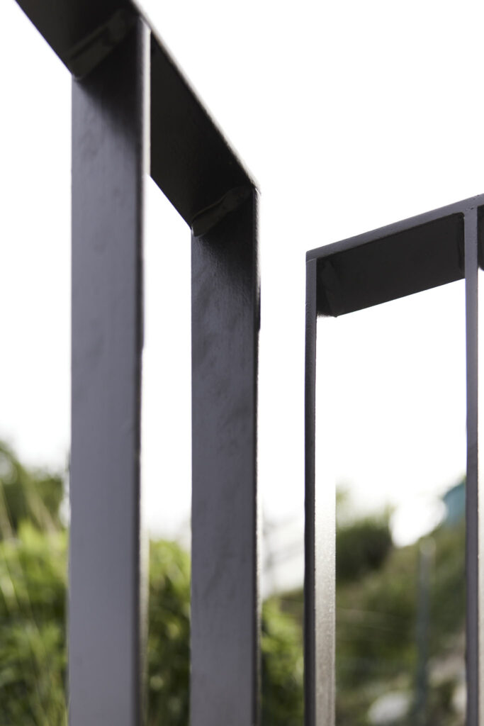 Detailaufnahme von schwarzem Metallgeländer vor verschwommener Landschaft
