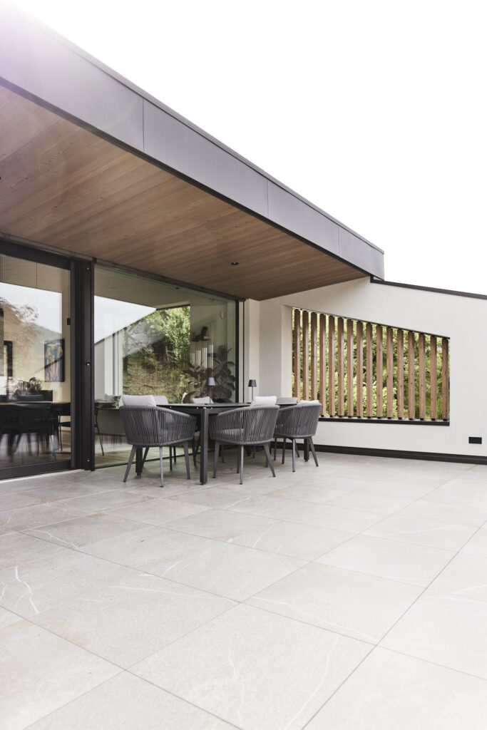 Moderne Terrasse mit Glasfront und eleganten Gartenmöbeln