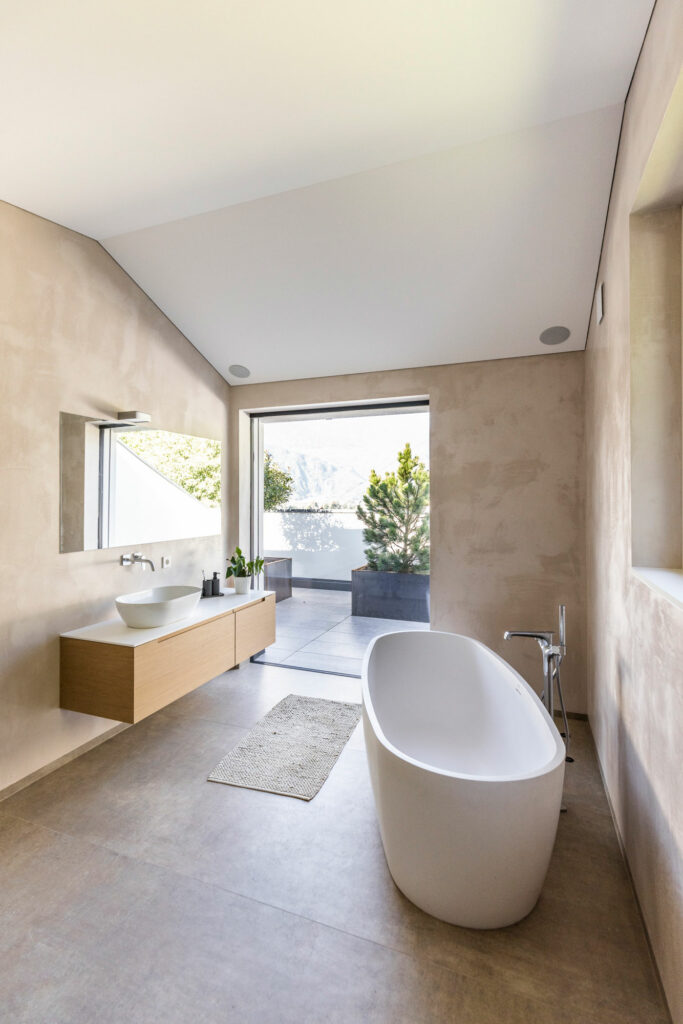 Modernes Badezimmer mit freistehender Badewanne und Bergblick.