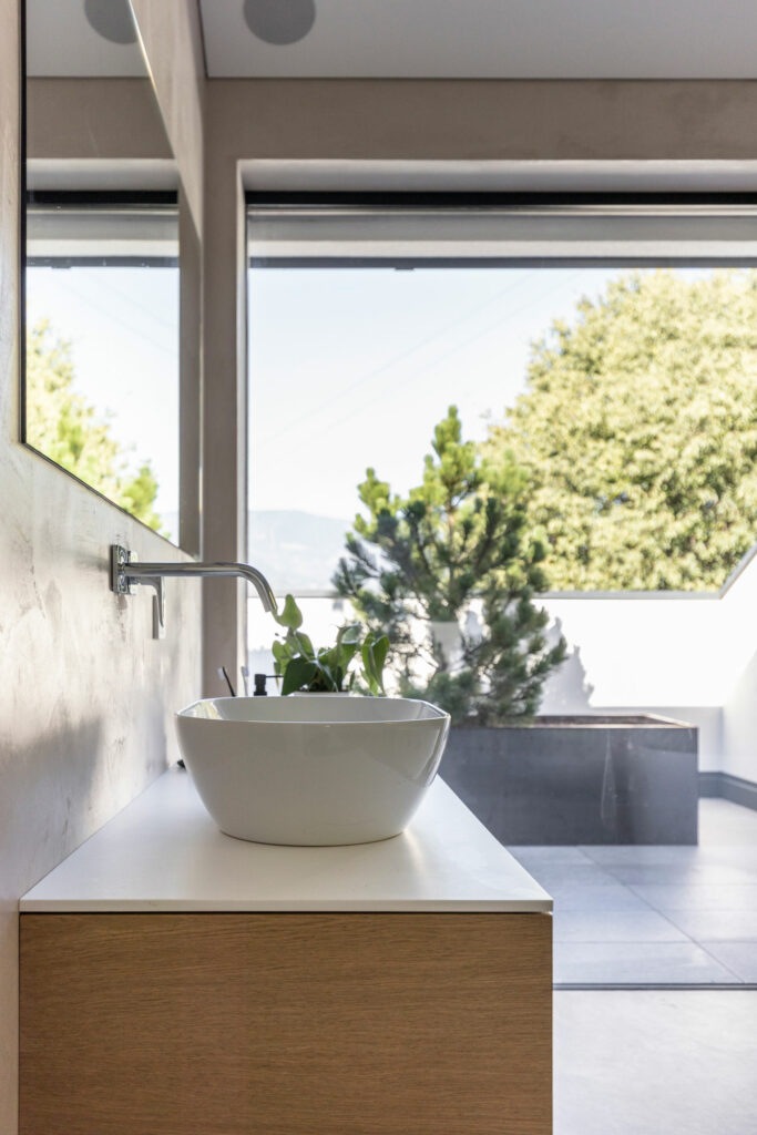 Modernes Waschbecken mit Ausblick auf Terrasse und Pflanzen