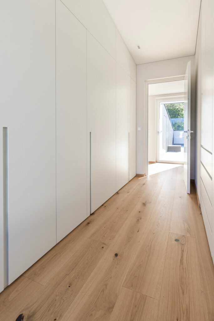 Lichtdurchfluteter Flur mit Holzboden und weißen Schränken