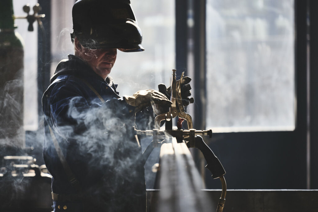 Schweißer in Werkstatt bei Metallverarbeitung, rauchige Atmosphäre