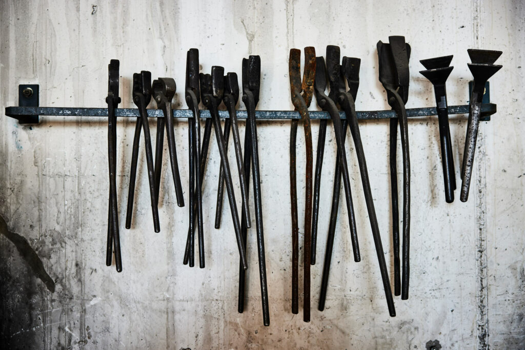 Verschiedene Metallwerkzeuge hängen an Wandhalterung.