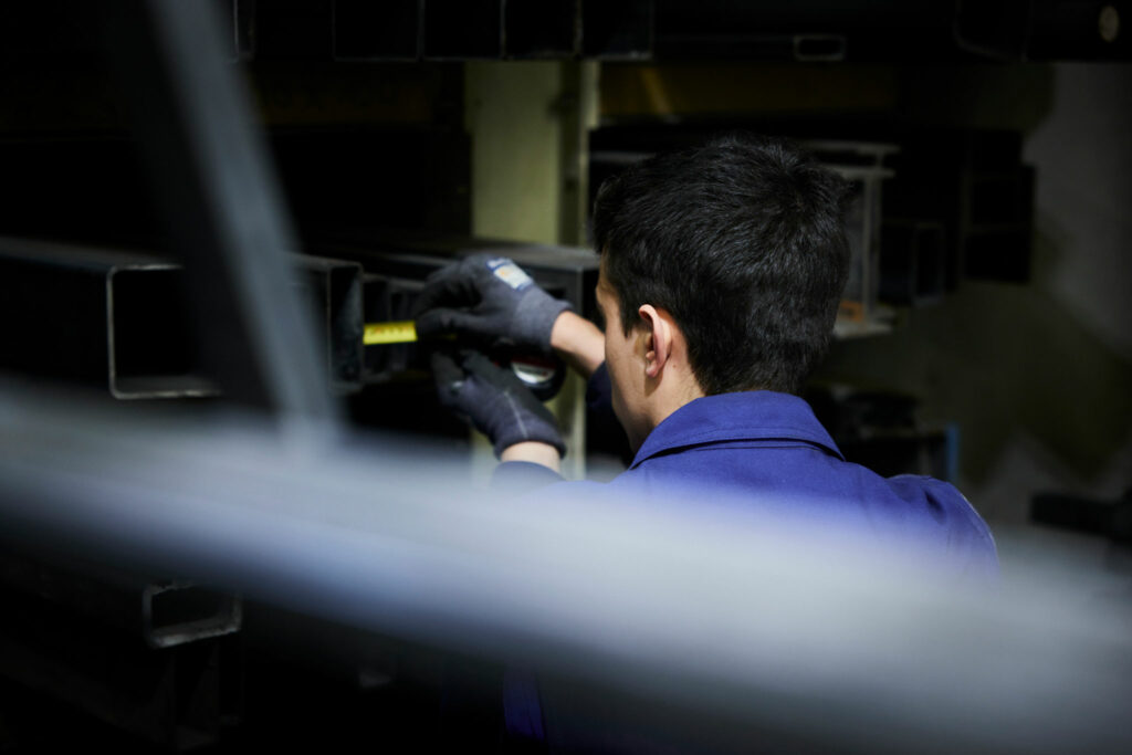 Arbeiter misst Metallrohr in einer Werkstatt