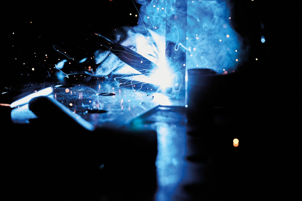 Funken und Licht beim Metallschweißen in dunkler Werkstatt