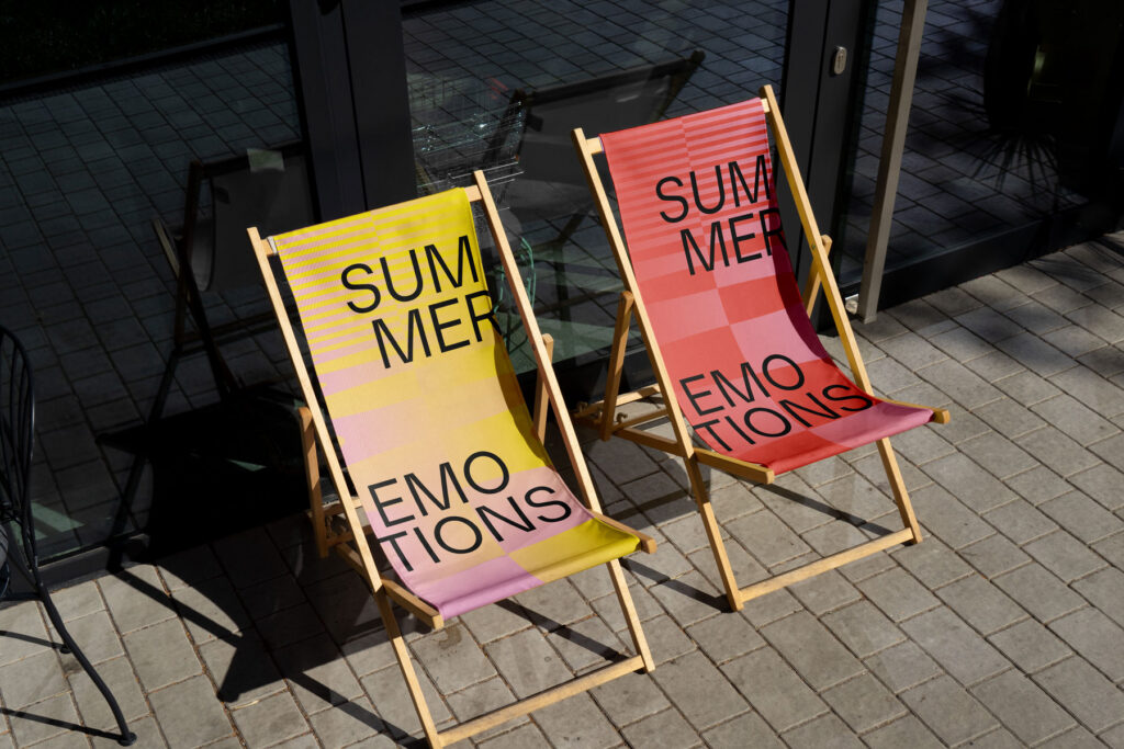 Zwei bunte Liegestühle mit Aufschrift 'Summer Emotions' auf Terrasse.