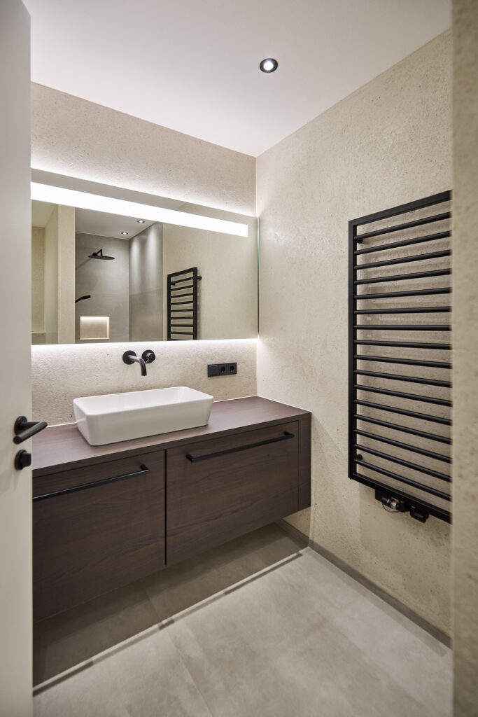 Modernes Badezimmer mit Waschbecken, Spiegel und Handtuchheizkörper.