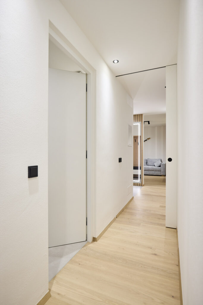 Moderner Flur mit hellem Holzfußboden und eingebauter Beleuchtung