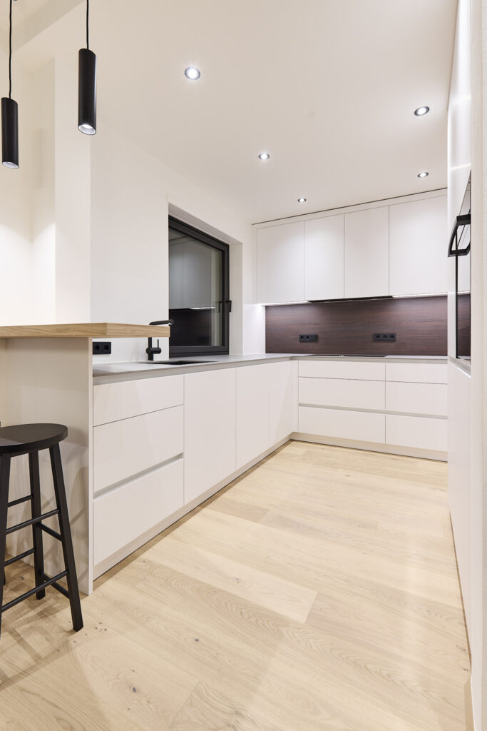 Moderne, minimalistische Küche mit hellen Holzböden und weißen Schränken.