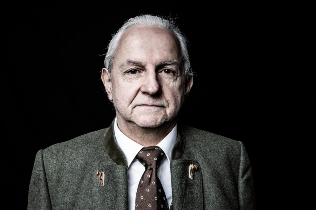 Älterer Mann in traditioneller Kleidung vor dunklem Hintergrund
