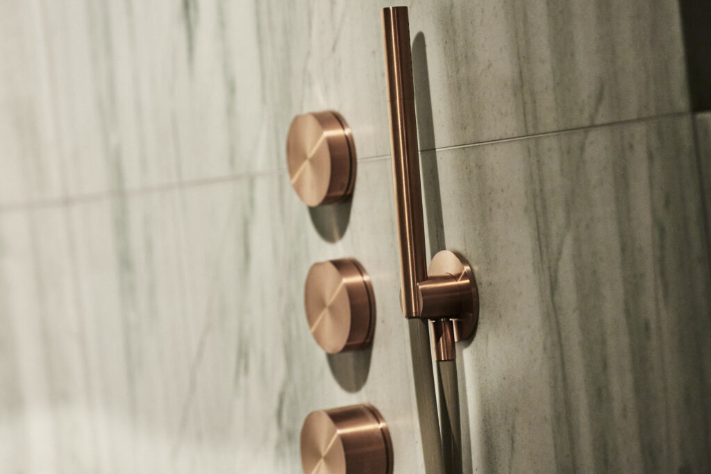 Detailansicht einer Dusche mit kupferfarbenen Armaturen