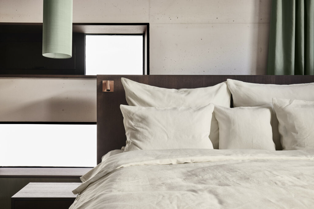 Modernes Hotelzimmer mit weißen Kissen und grünen Vorhängen