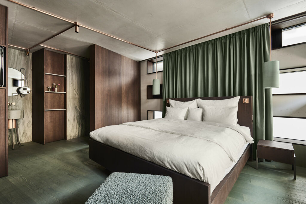 Modernes Hotelzimmer mit Holzwänden und grünem Vorhang