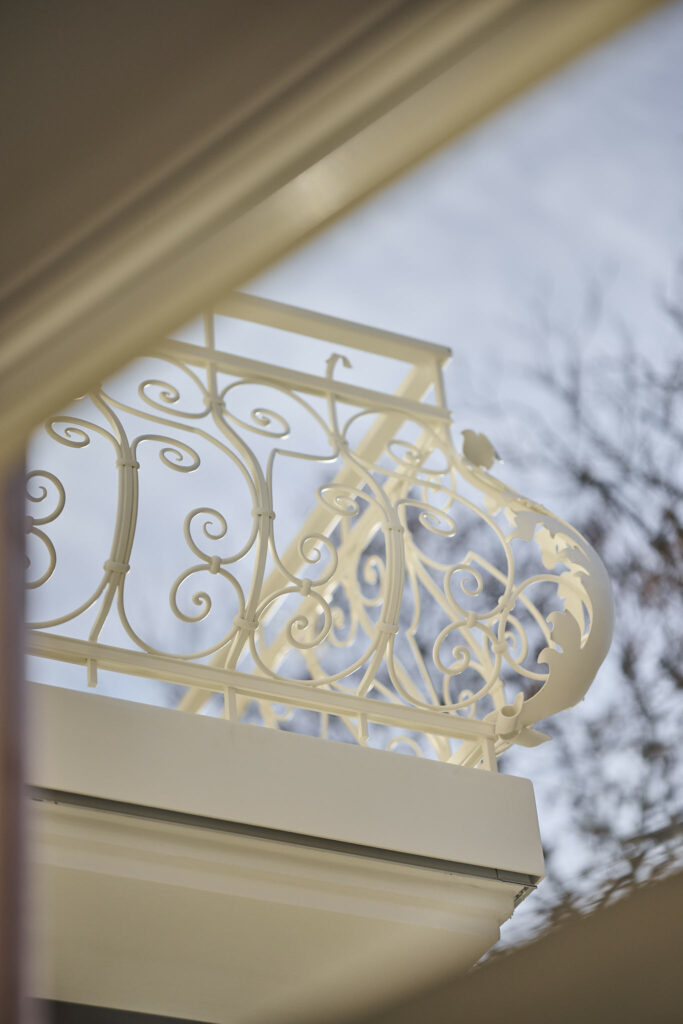 Detailaufnahme eines weißen, kunstvollen Balkon-Geländers