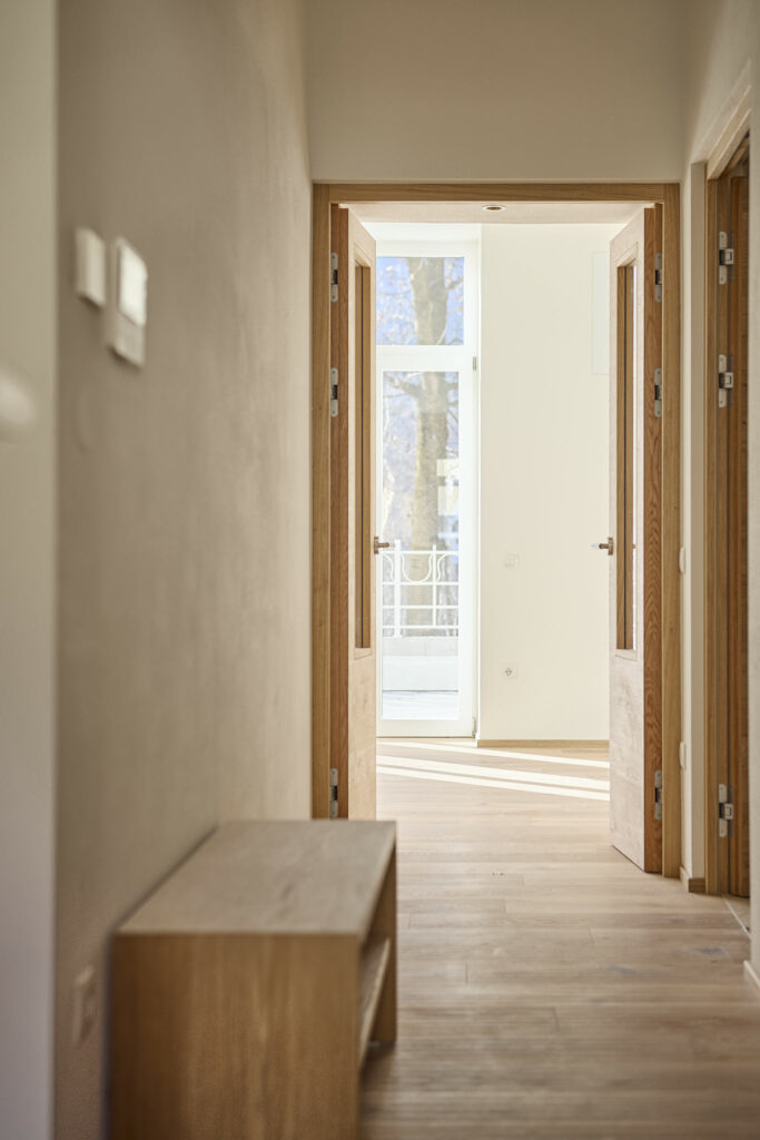 Heller Flur mit Holztüren und Blick ins Freie