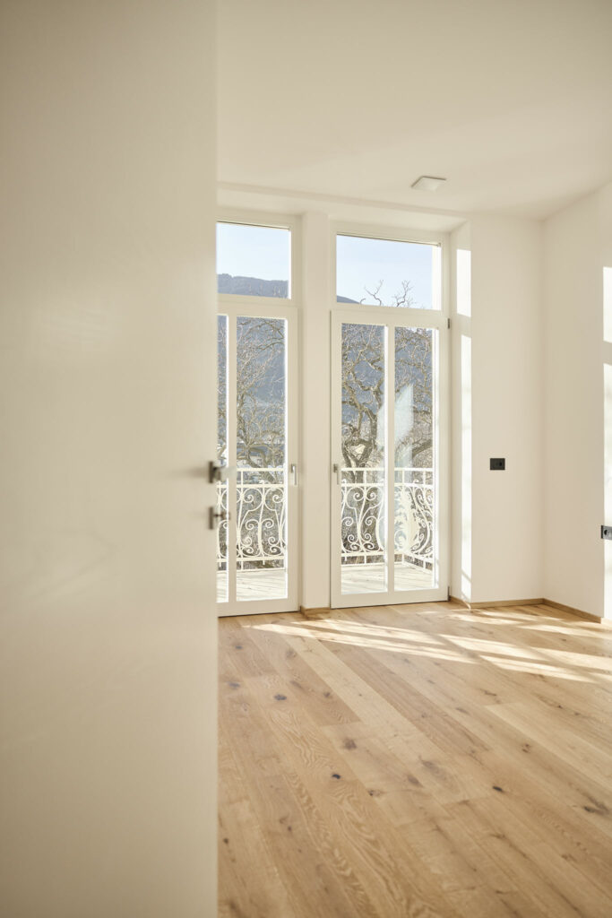 Helles Zimmer mit Holzboden, Blick auf Balkon und Berge