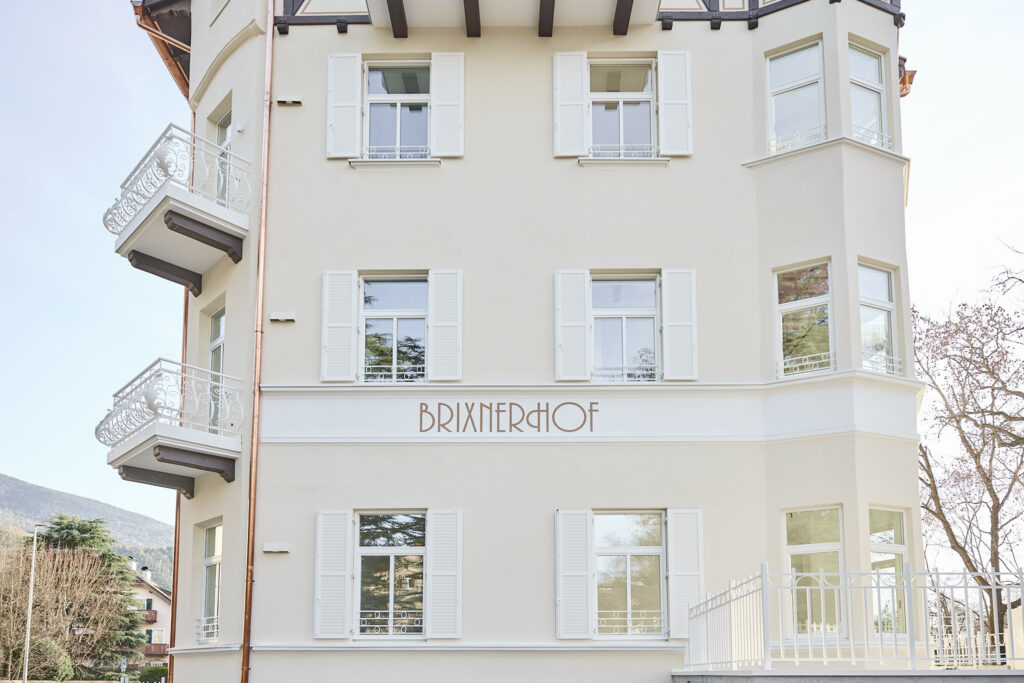 Fassade des Brixnerhofs mit weißen Fensterläden und Balkonen.