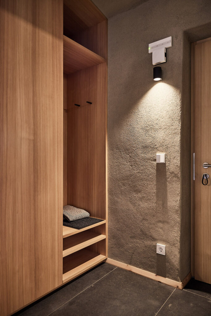 Holzschrank und Wandleuchte in moderner Ferienwohnung