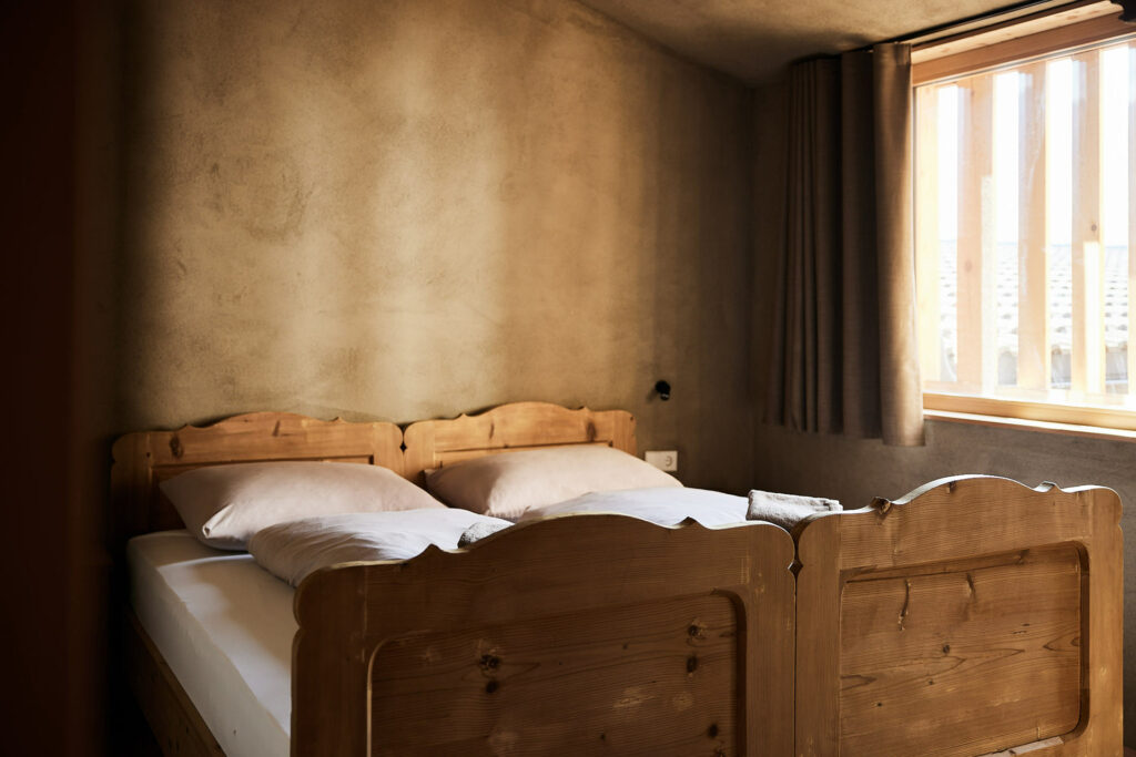 Gemütliches Doppelbett in rustikalem Schlafzimmer mit Holzmöbeln