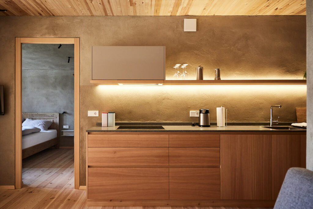 Moderne Küchenzeile mit Holzverkleidung und beleuchtetem Regal.