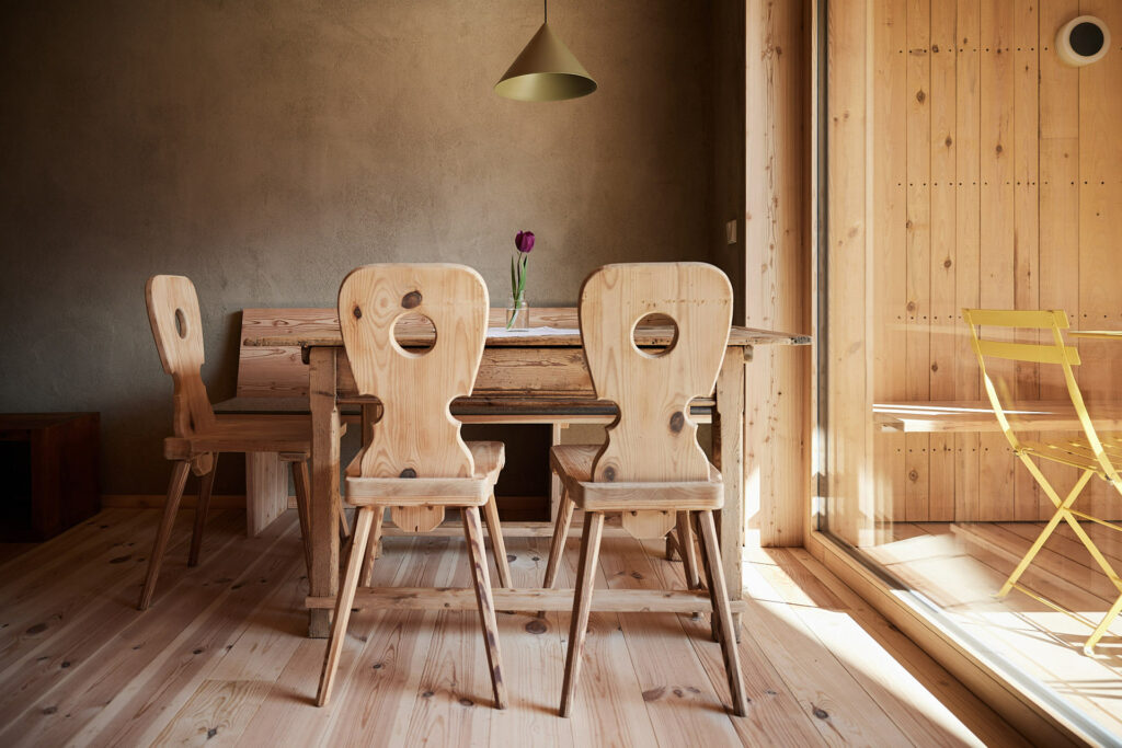 Holztisch und -stühle in lichtdurchflutetem Raum mit Tulpe