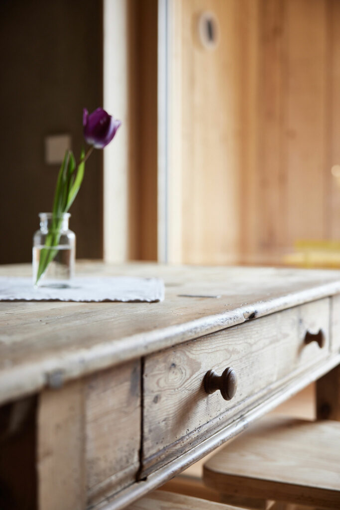 Rustikaler Holztisch mit violetter Tulpe im Glas