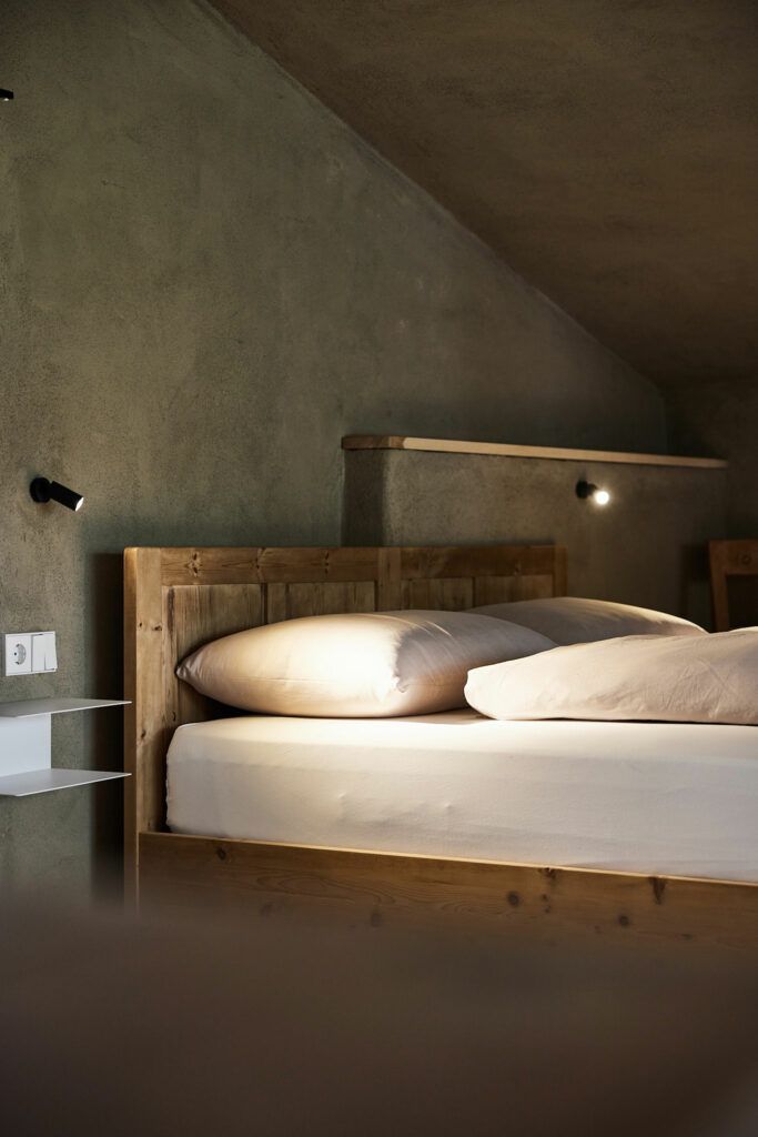 Minimalistisches Schlafzimmer mit Holzbett und Betonwandbeleuchtung