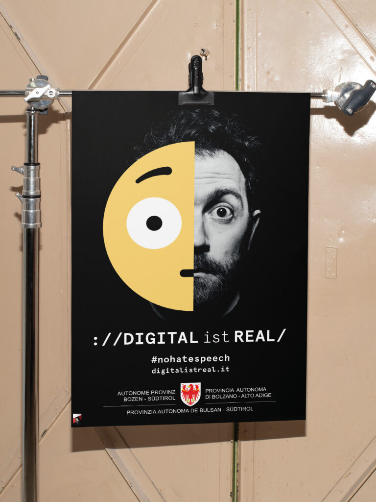 Plakat mit halbem Gesicht und Emoji, Text: 'Digital ist real'.
