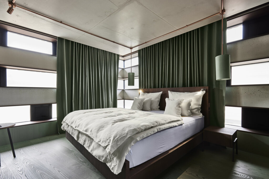Modernes Schlafzimmer mit grünen Vorhängen und eleganter Beleuchtung