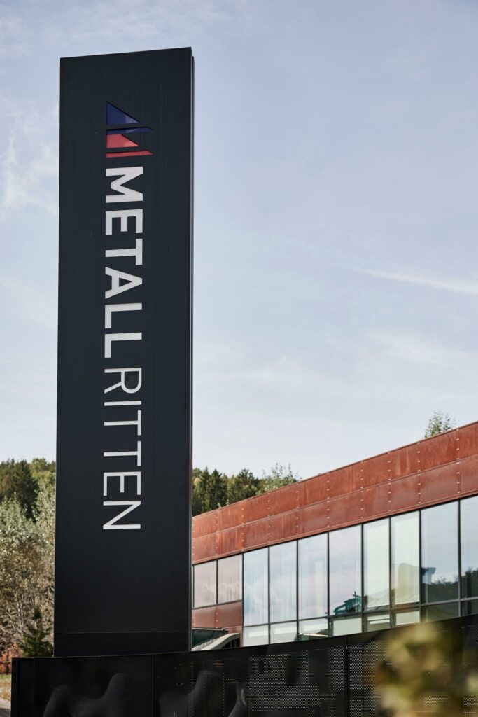Firmenschild von Metall Ritten vor modernem Gebäude