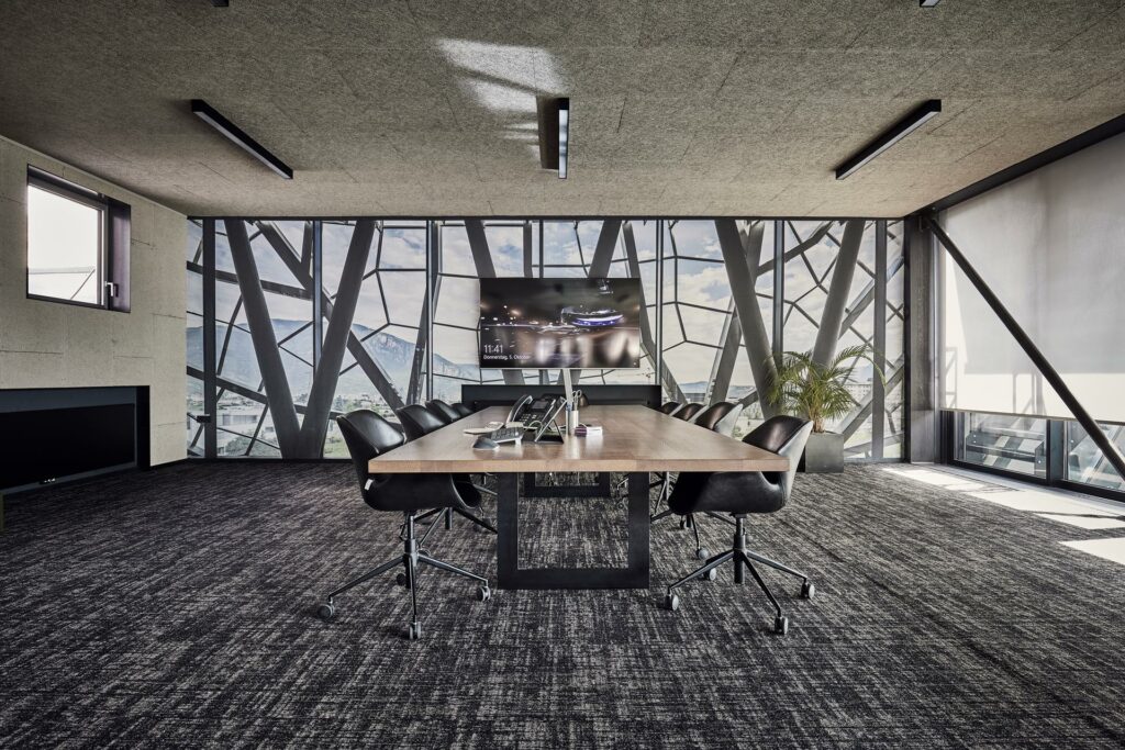 Konferenzraum mit modernem Tisch, Panoramafenster und Bergblick.