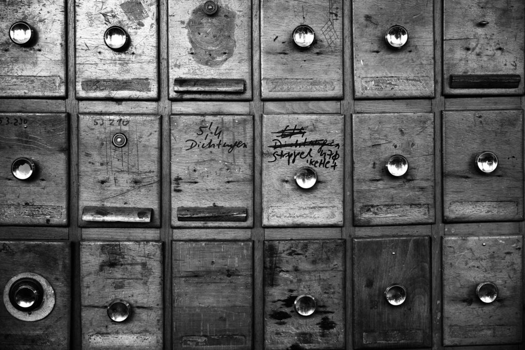 Alte Holzschubladen mit handschriftlichen Notizen und glänzenden Griffen