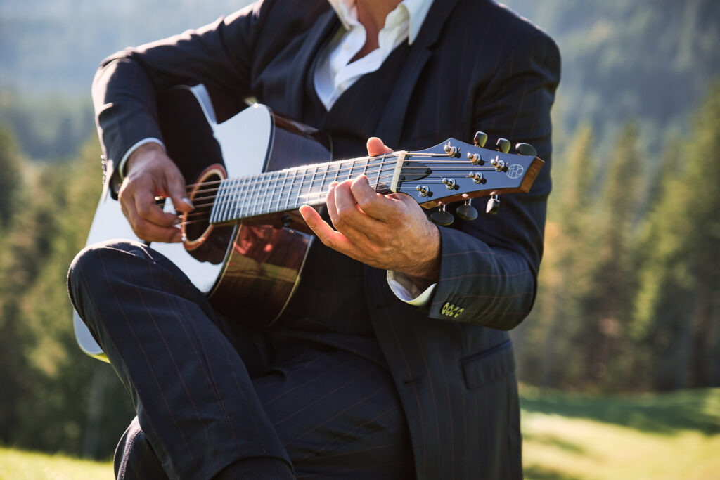 Mann im Anzug spielt Gitarre in natürlicher Umgebung