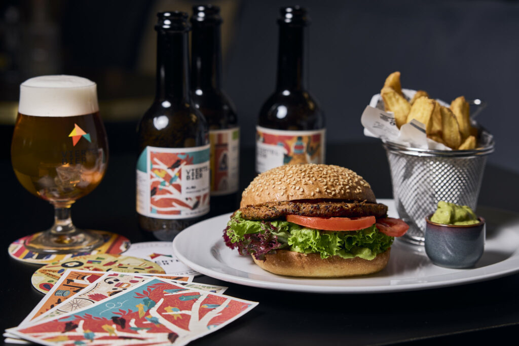Burger mit Pommes, Bierflasche und Glas auf Tisch