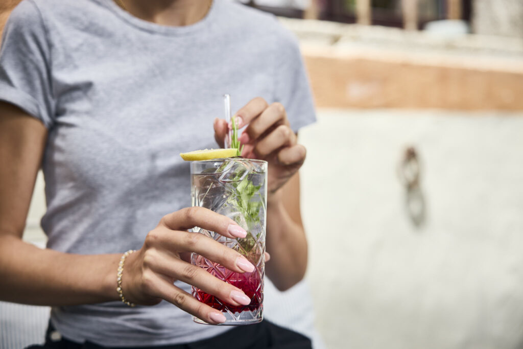 Frau hält erfrischenden Cocktail mit Limette und Minze