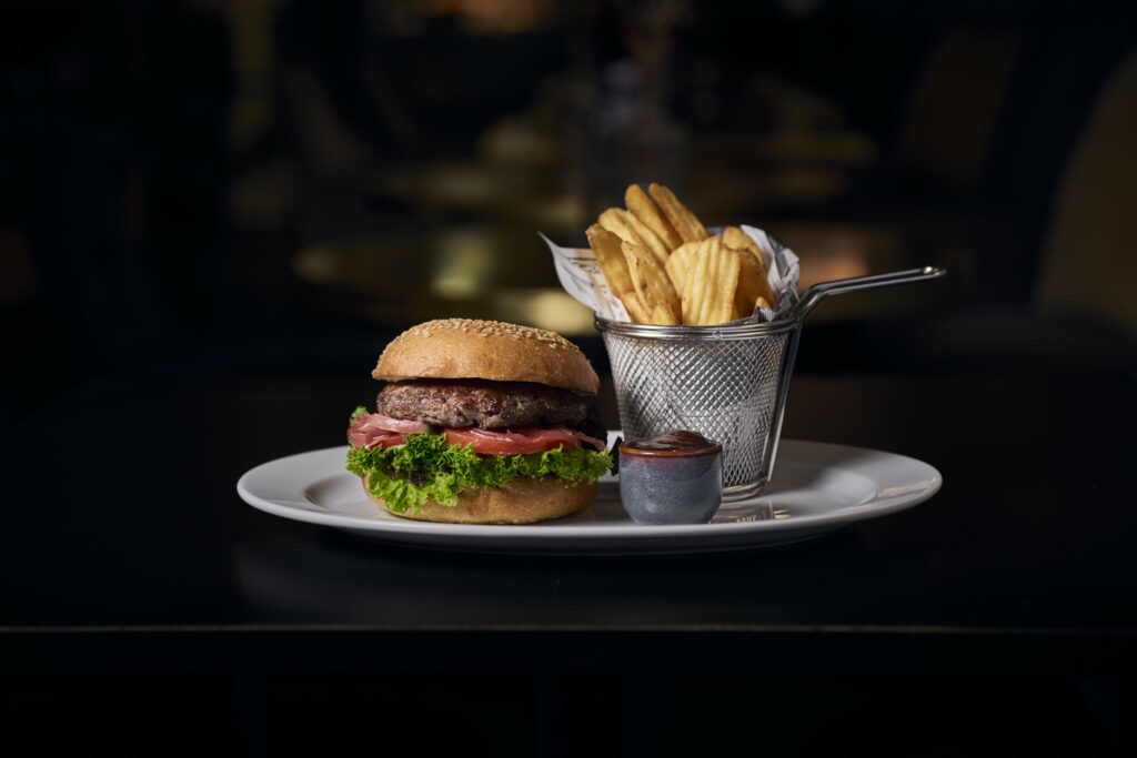 Burger mit Pommes und Ketchup auf weißem Teller