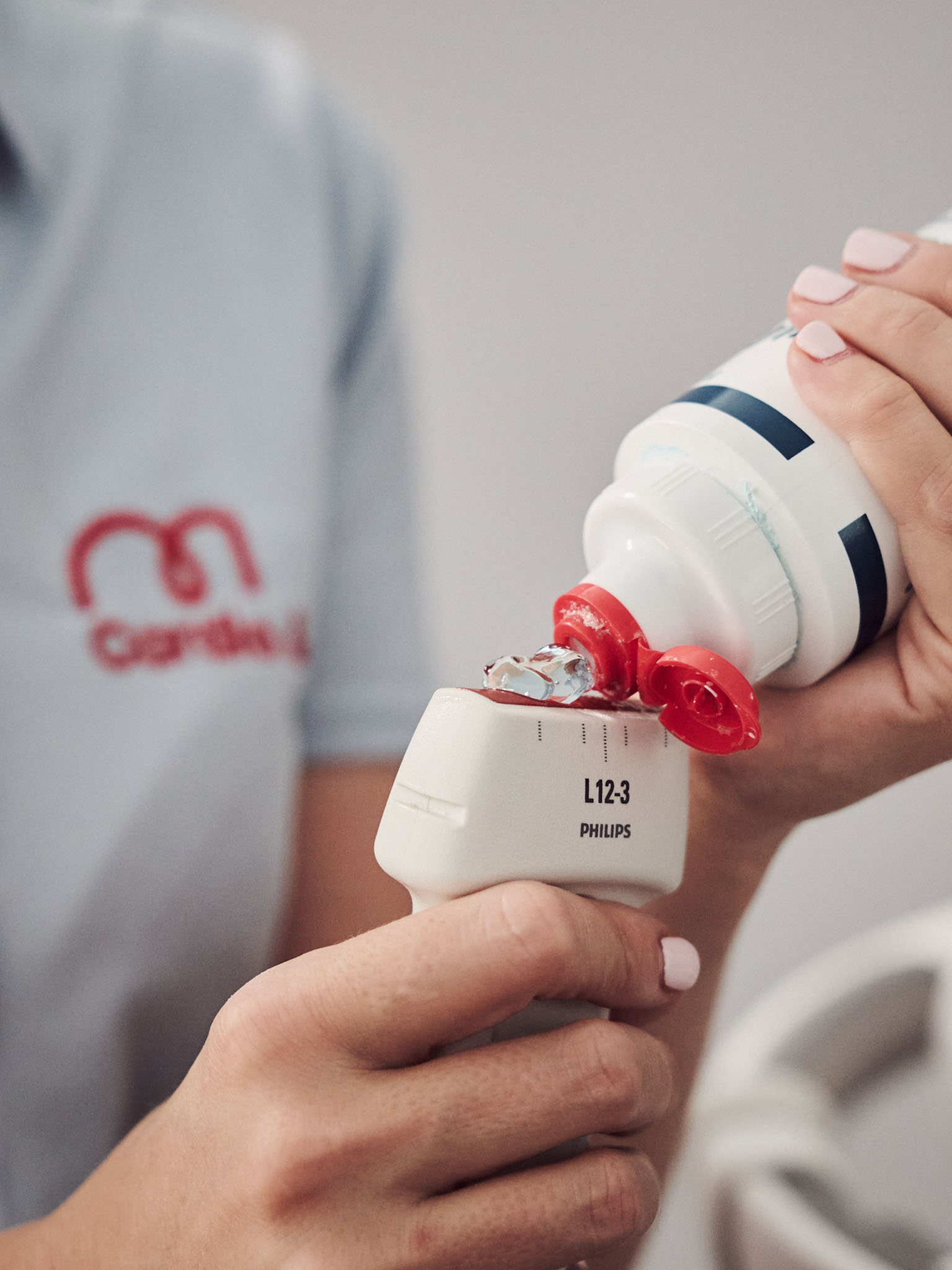 Person trägt Gel auf Ultraschallgerät auf.
