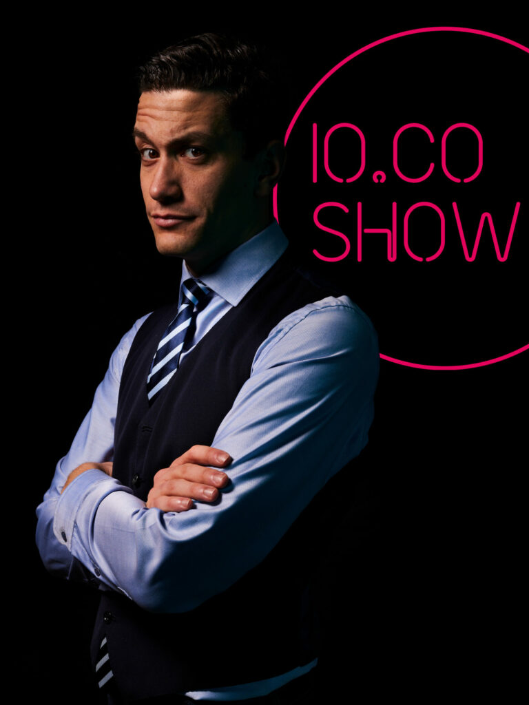 Mann im Anzug vor IO.CO SHOW Logo