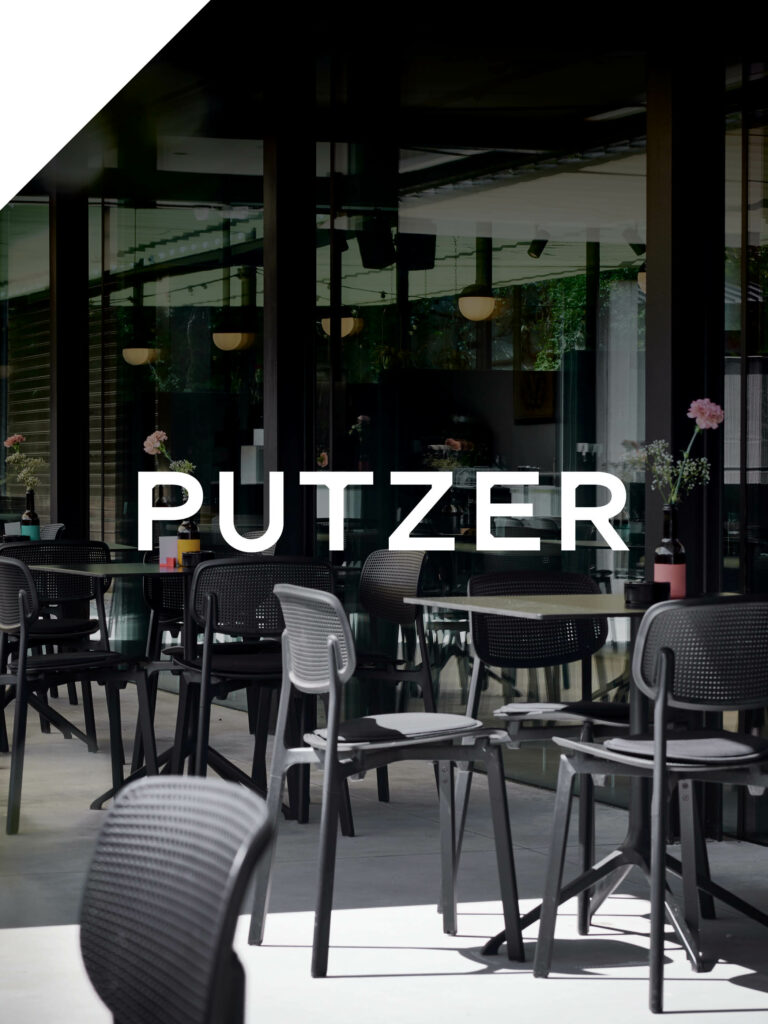 Moderne Terrasse mit schwarzen Stühlen und Blumenvasen, PUTZER-Schriftzug