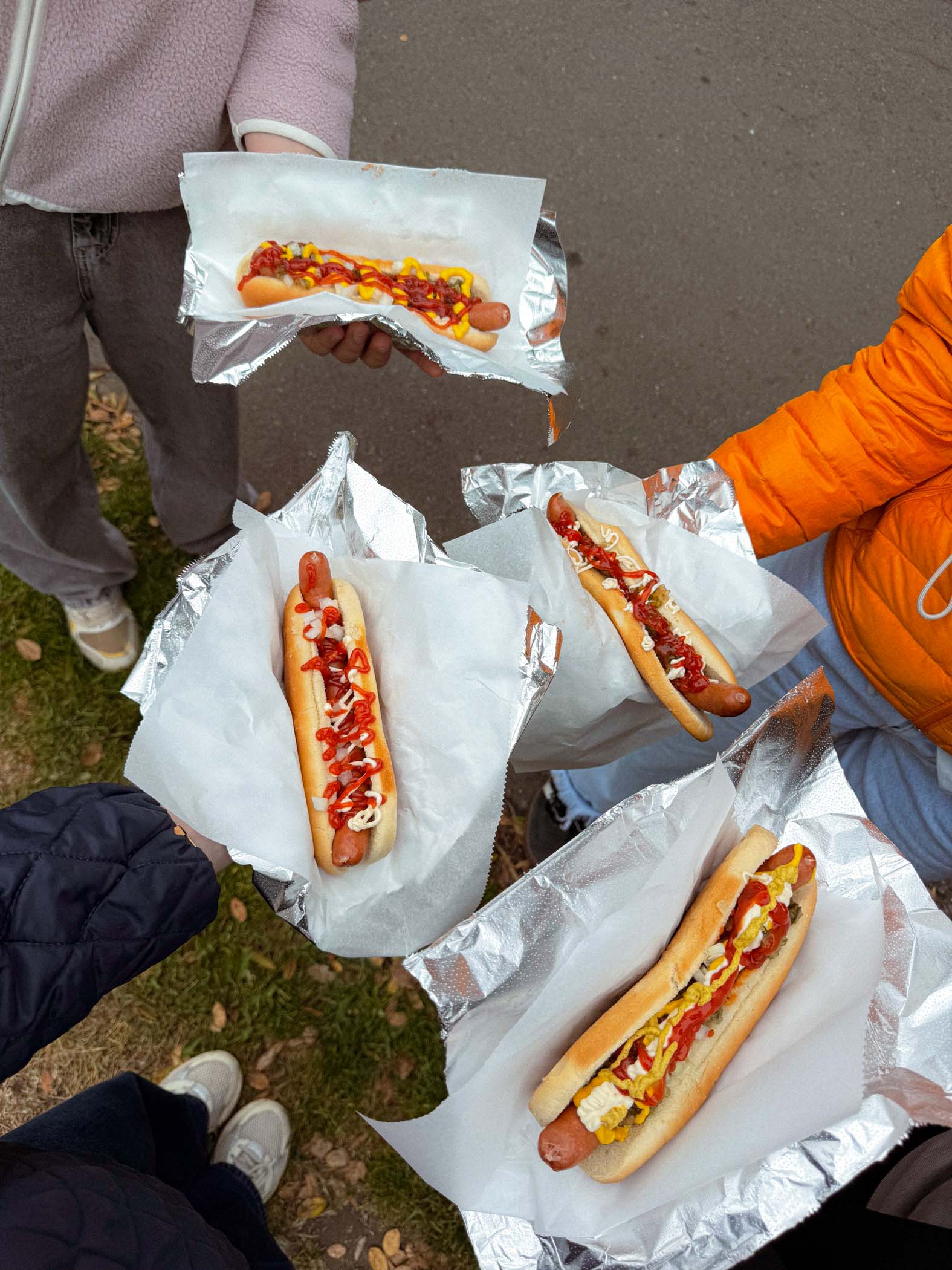 Vier Personen halten Hotdogs mit Ketchup und Senf